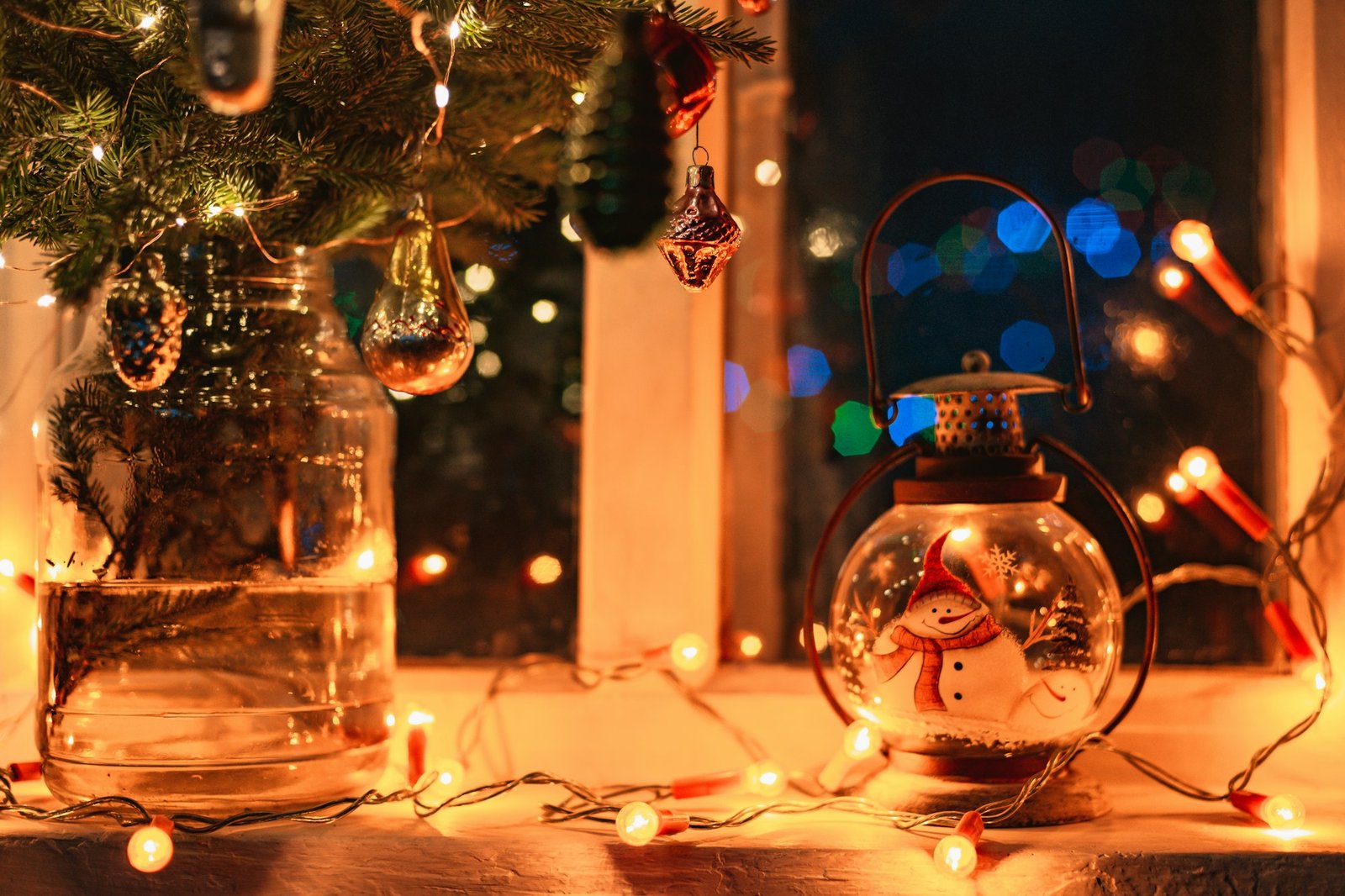 christmas decorations on the window at night, fir branches, retro glass decorations, lights garlands