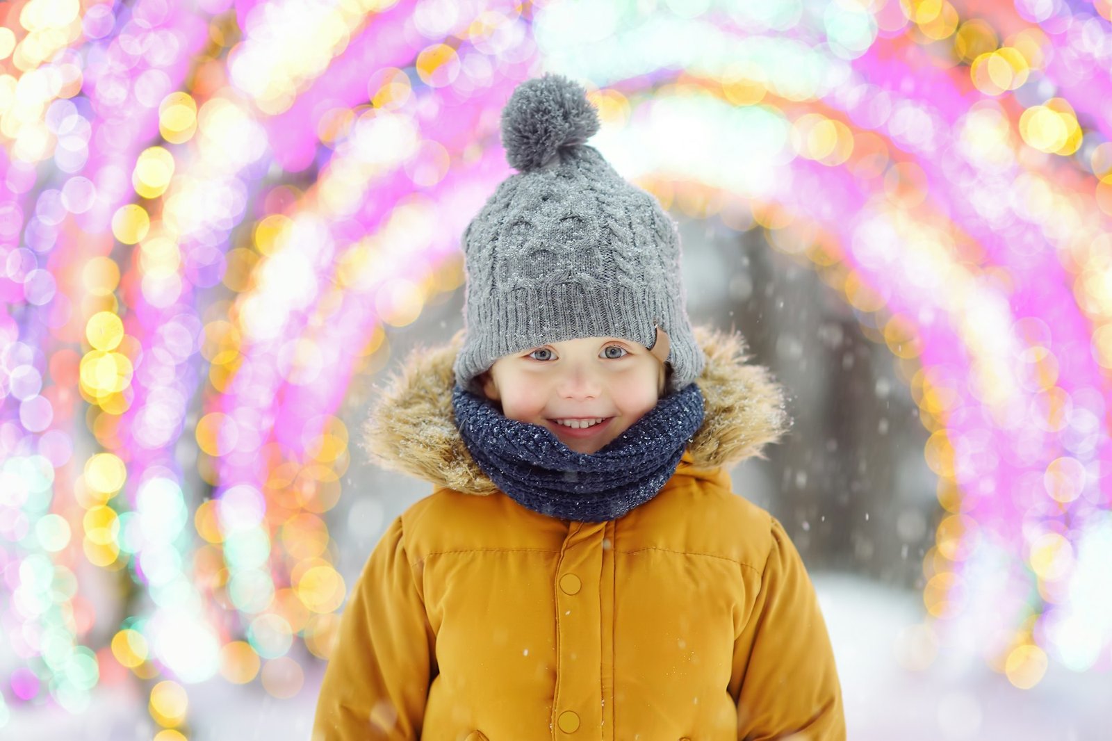 Little boy is admiring a large glowing street decoration on Christmas fair