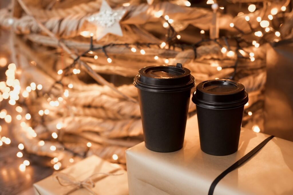 Mockup of black recycling paper cups with caps takeout on christmas decoration lights background