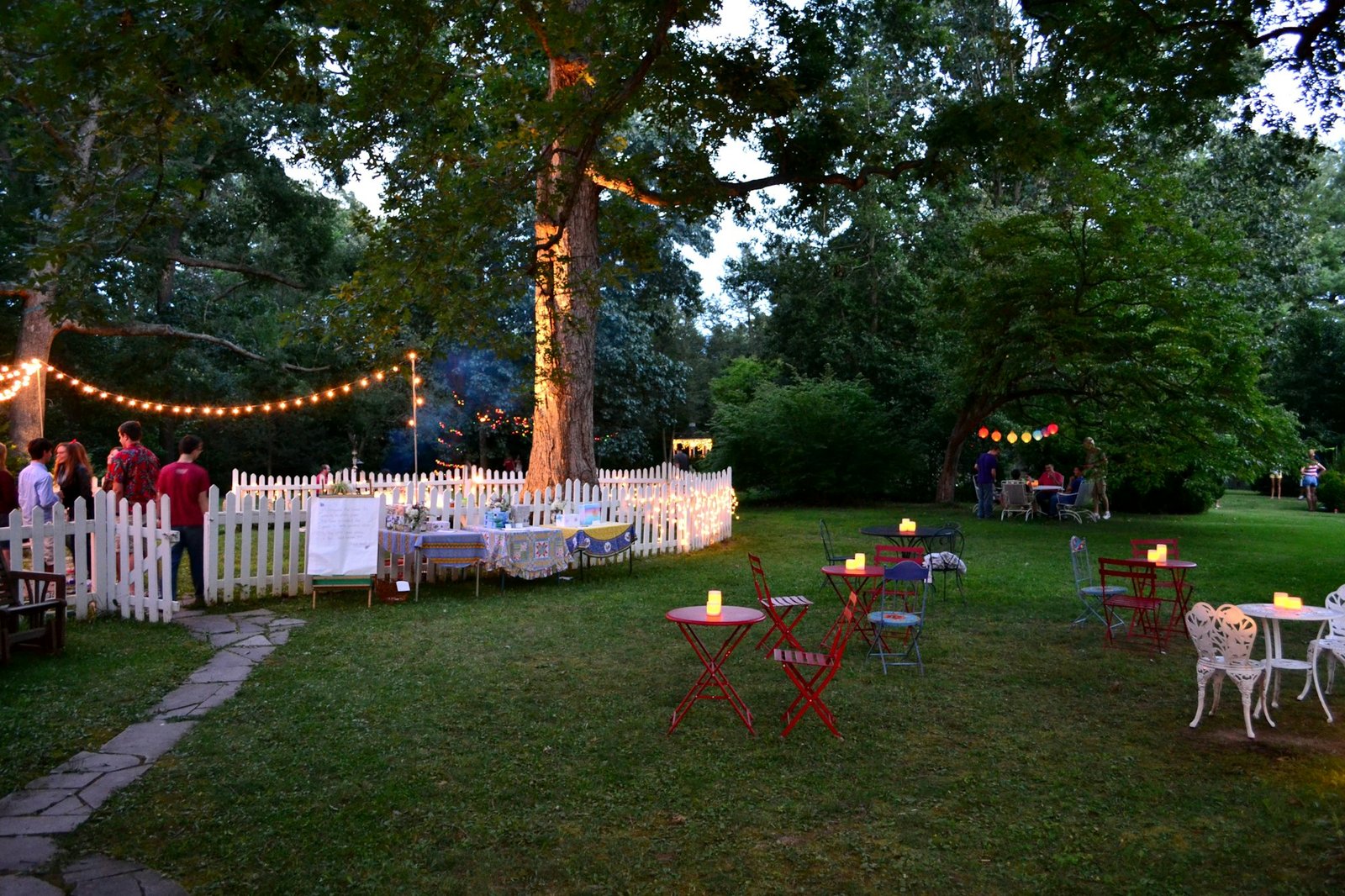 Party in a backyard garden with lights strung in the trees creating a magical atmosphere