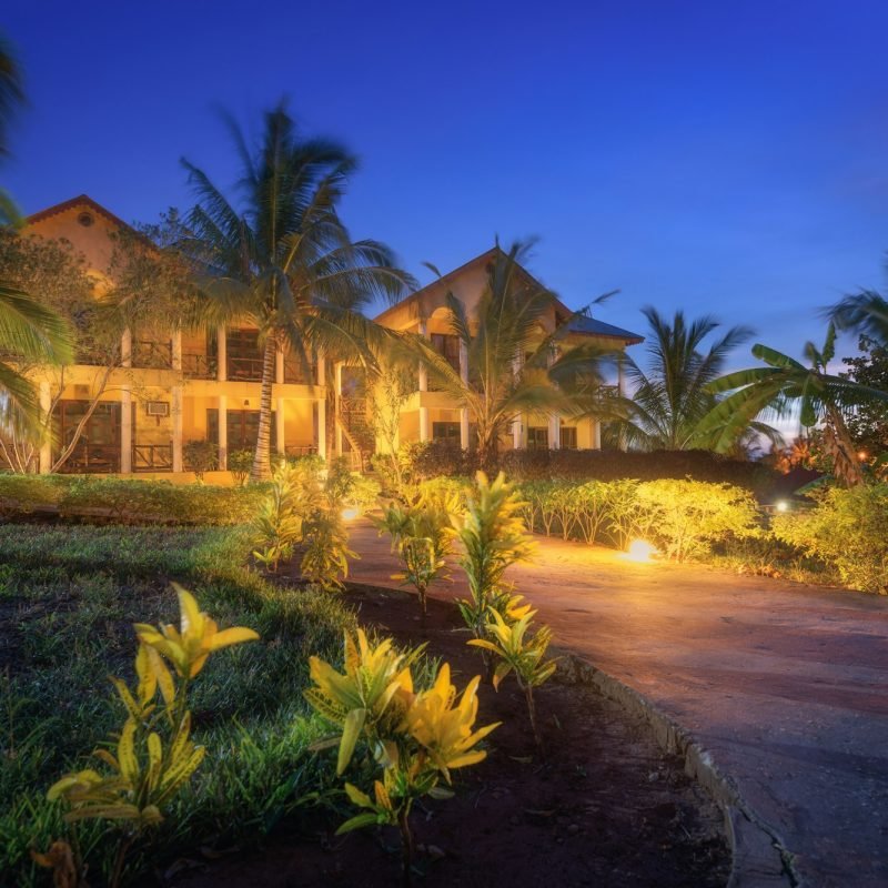 Amazing hotel with lighted paths in flowers garden in summer night
