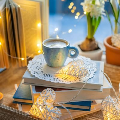 Coffee cup, open book, spring flowers, sparkle lighting garland on window sill